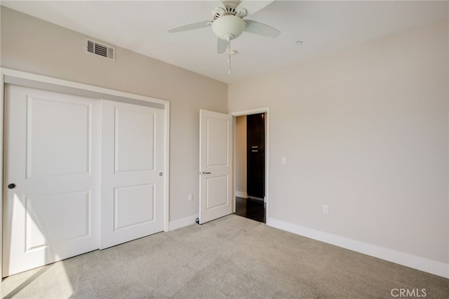 unfurnished bedroom featuring light carpet, a closet, and ceiling fan