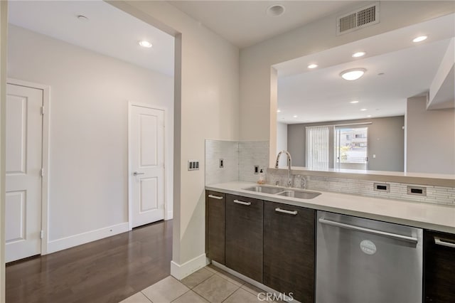 kitchen featuring tasteful backsplash, sink, light wood-type flooring, dark brown cabinetry, and stainless steel dishwasher