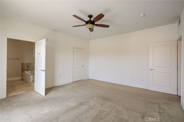 unfurnished bedroom featuring connected bathroom, light colored carpet, and ceiling fan