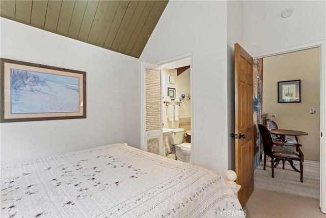 carpeted bedroom with vaulted ceiling and ensuite bathroom