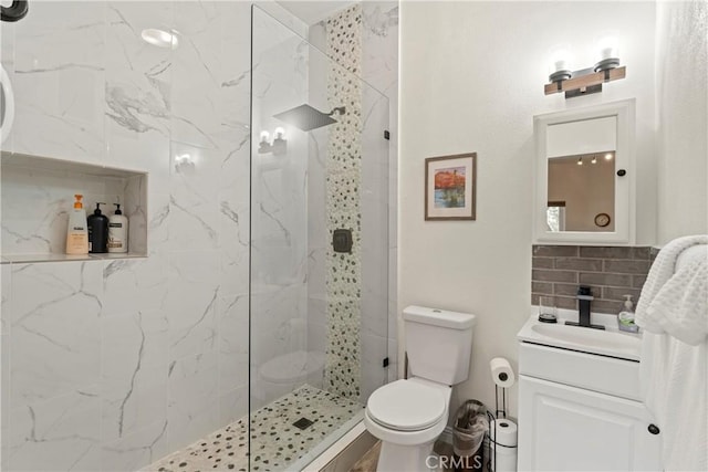 bathroom featuring vanity, toilet, a tile shower, and decorative backsplash