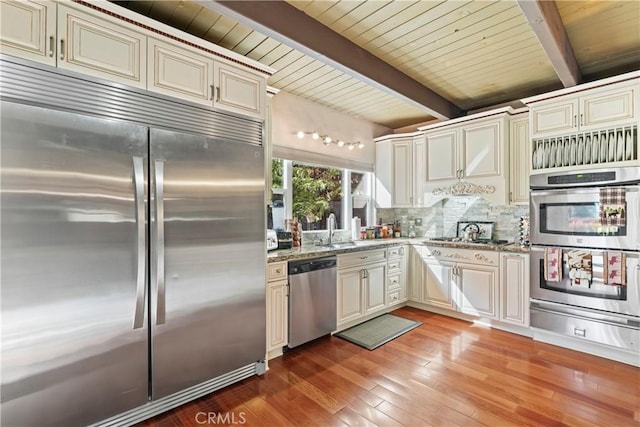 kitchen with tasteful backsplash, wooden ceiling, stainless steel appliances, beam ceiling, and light stone countertops