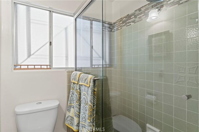 bathroom featuring toilet and an enclosed shower