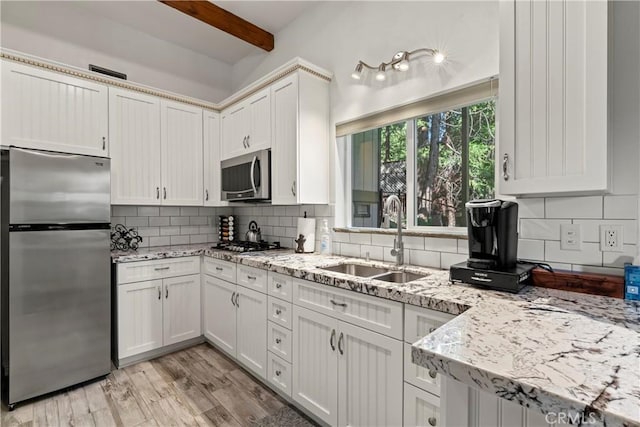 kitchen with tasteful backsplash, white cabinetry, appliances with stainless steel finishes, and sink