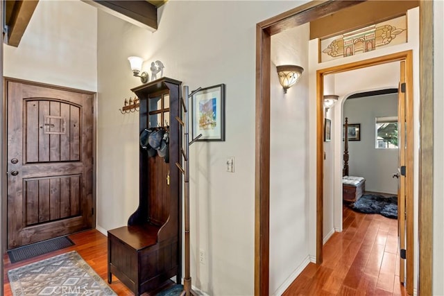 hall with wood-type flooring and beam ceiling