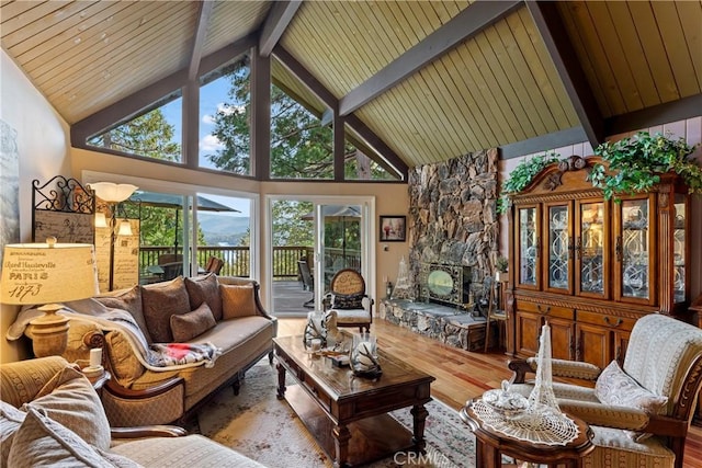 living room featuring beamed ceiling, a stone fireplace, hardwood / wood-style floors, and high vaulted ceiling