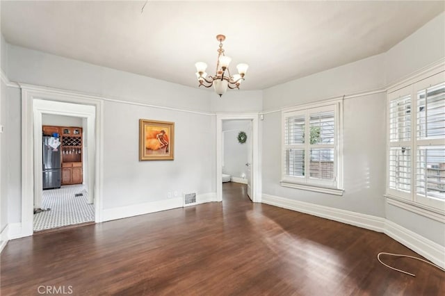 unfurnished room with a notable chandelier and dark hardwood / wood-style floors