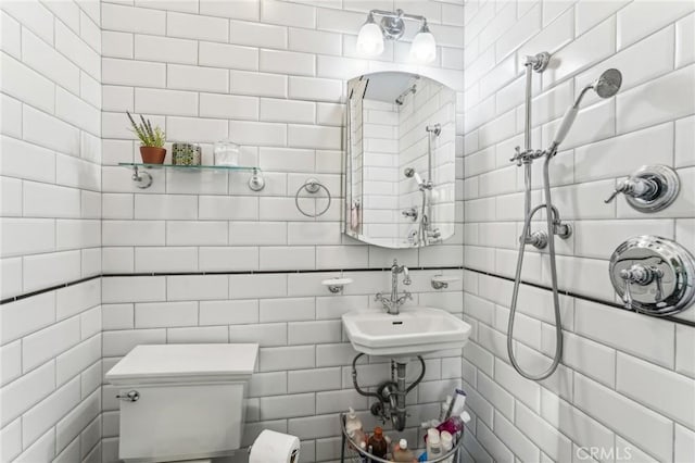 bathroom with tiled shower, toilet, tile walls, and sink