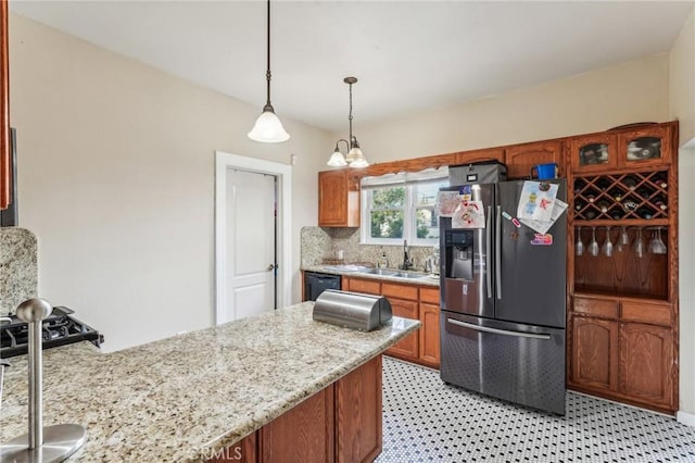 kitchen featuring sink, black dishwasher, backsplash, stainless steel fridge, and decorative light fixtures