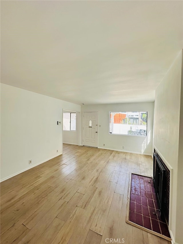 unfurnished living room with a fireplace and light hardwood / wood-style floors