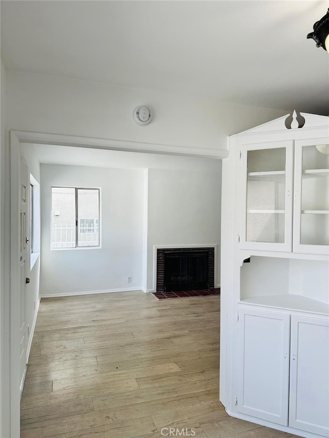 unfurnished living room featuring a brick fireplace and light hardwood / wood-style floors