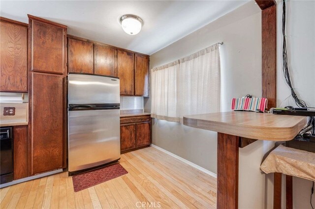 kitchen featuring dishwasher, stainless steel fridge, and light hardwood / wood-style floors