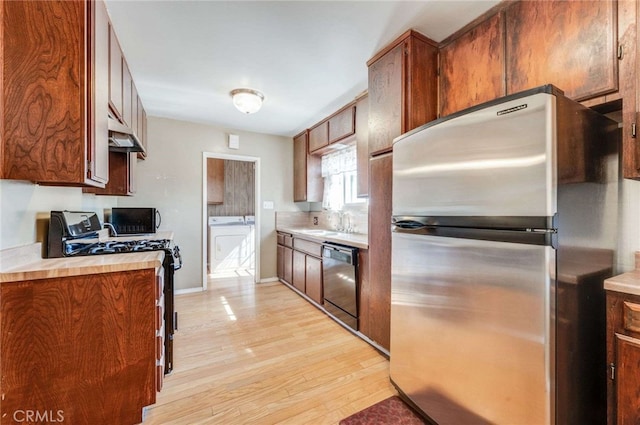 kitchen with black appliances, light wood-type flooring, and sink