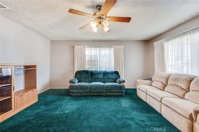 living room featuring ceiling fan, a textured ceiling, and dark colored carpet