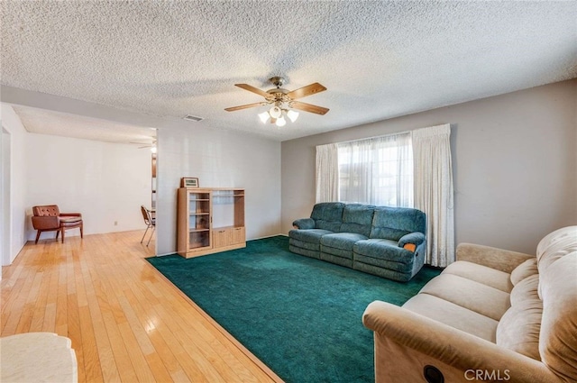 living room featuring ceiling fan, a textured ceiling, and hardwood / wood-style flooring