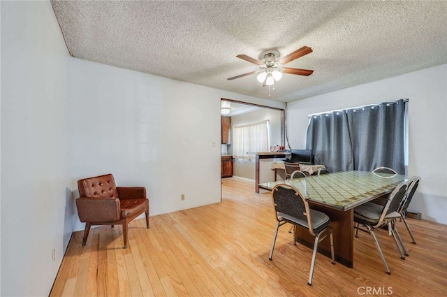 dining space featuring ceiling fan, light hardwood / wood-style floors, and a textured ceiling