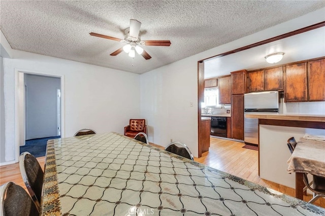 bedroom featuring ceiling fan, light wood-type flooring, a textured ceiling, and stainless steel refrigerator