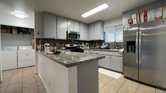 kitchen with stainless steel appliances, washing machine and clothes dryer, decorative backsplash, and light tile patterned flooring