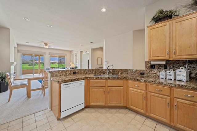 kitchen with dishwasher, dark stone counters, sink, ceiling fan, and kitchen peninsula