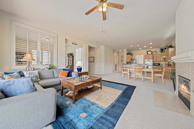 carpeted living room featuring ceiling fan and a tile fireplace