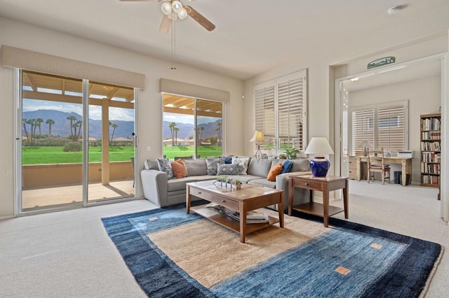 living room with a mountain view, carpet flooring, and ceiling fan