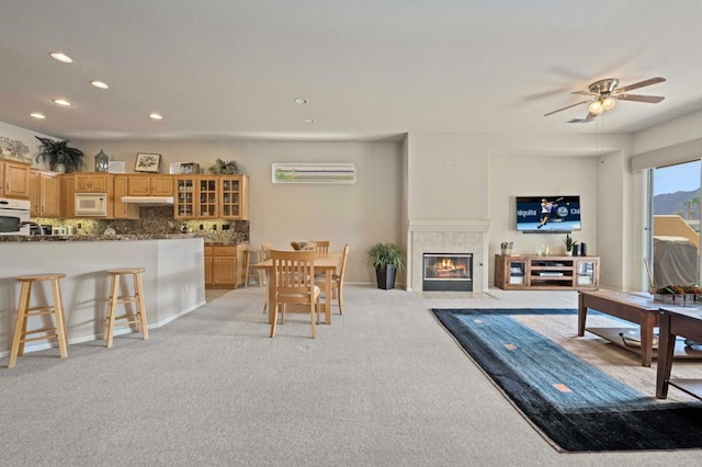 living room featuring a fireplace, light colored carpet, and ceiling fan