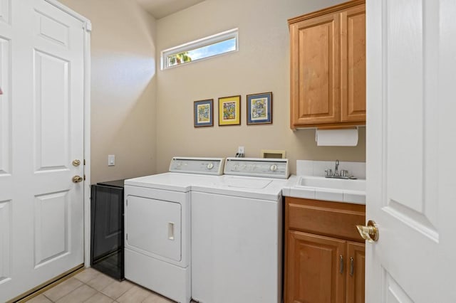 laundry area with cabinets, independent washer and dryer, light tile patterned floors, and sink