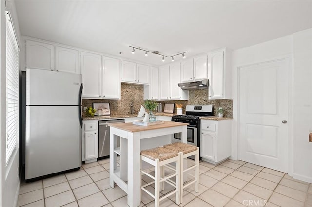 kitchen featuring wooden counters, appliances with stainless steel finishes, white cabinetry, tasteful backsplash, and light tile patterned flooring