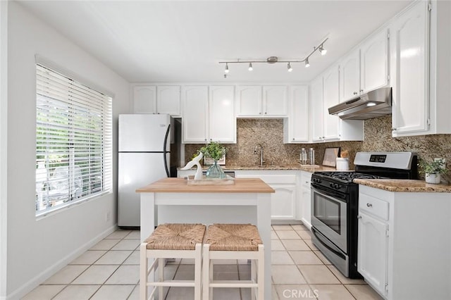 kitchen featuring white cabinetry, stainless steel appliances, a kitchen bar, and light tile patterned flooring