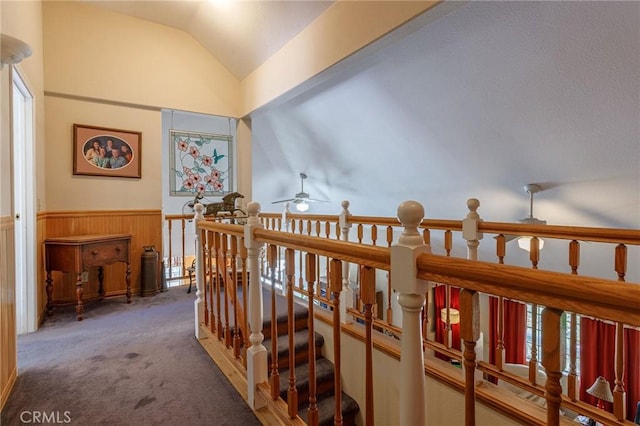 hallway featuring wood walls, carpet floors, and vaulted ceiling