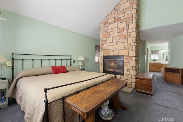 bedroom with ensuite bath, a fireplace, and vaulted ceiling