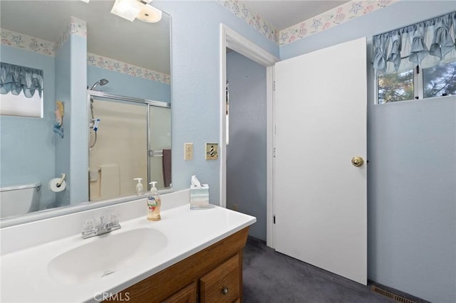 bathroom featuring vanity, toilet, and a shower with shower door