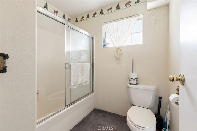 bathroom featuring toilet and bath / shower combo with glass door