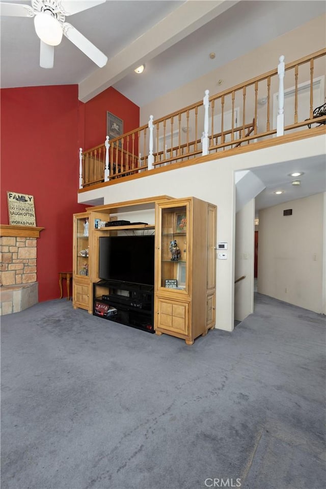 unfurnished living room with beam ceiling, ceiling fan, high vaulted ceiling, a fireplace, and carpet