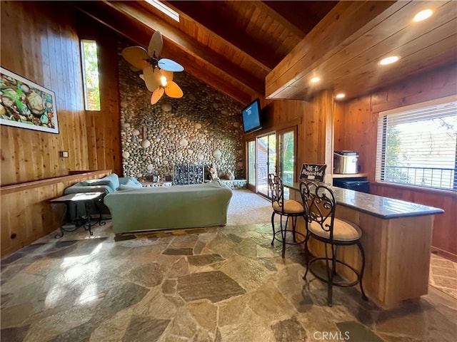 interior space featuring lofted ceiling with beams, wooden walls, ceiling fan, and wooden ceiling