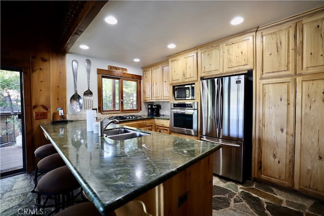 kitchen with stainless steel appliances, a breakfast bar, kitchen peninsula, and a healthy amount of sunlight