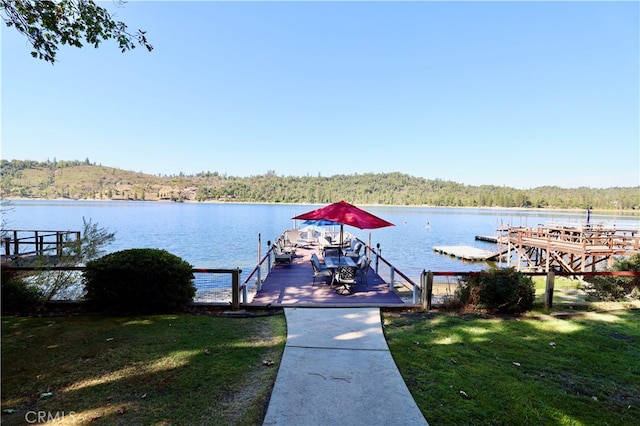 view of dock with a yard and a water view