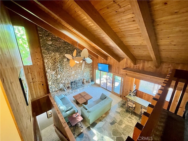 unfurnished living room with a healthy amount of sunlight, wooden walls, and vaulted ceiling with beams