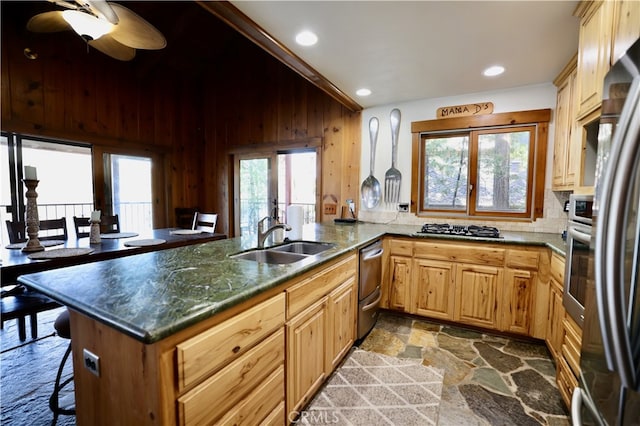 kitchen featuring wood walls, kitchen peninsula, sink, and a healthy amount of sunlight