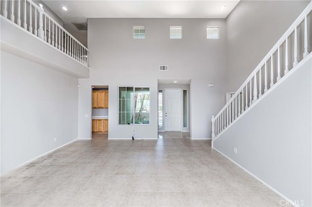 unfurnished living room with light tile patterned flooring and a towering ceiling