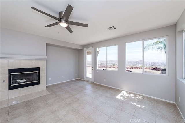 unfurnished living room with ceiling fan, light tile patterned floors, and a tile fireplace