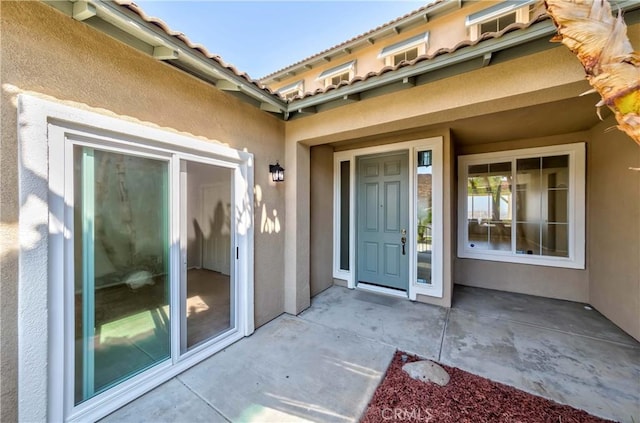 view of exterior entry with a patio area