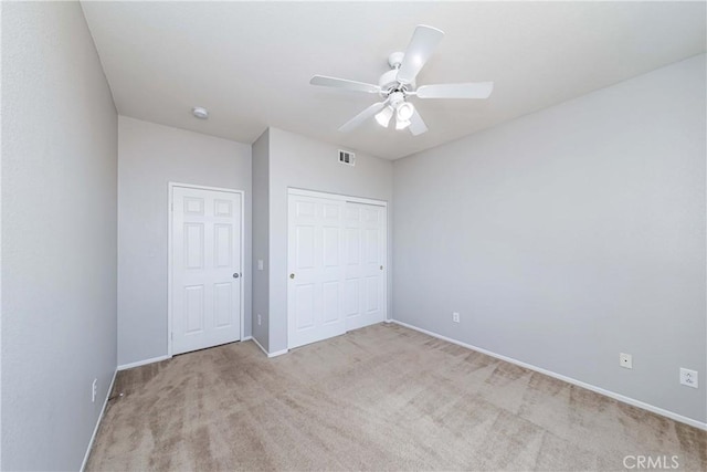 unfurnished bedroom with ceiling fan, light colored carpet, and a closet