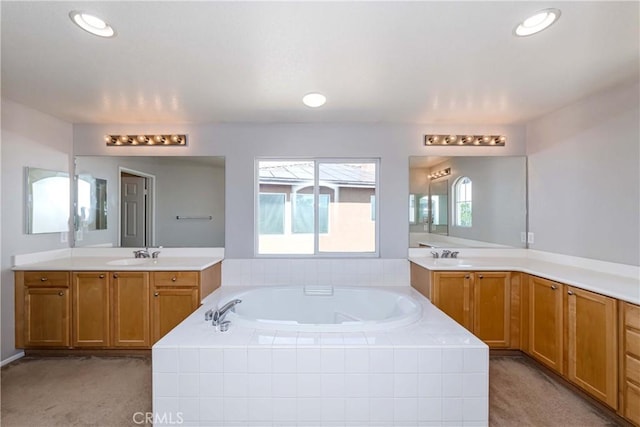 bathroom with a relaxing tiled tub and vanity