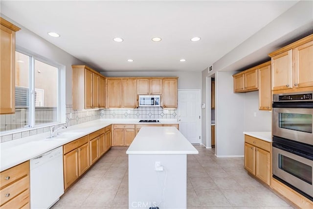 kitchen featuring tasteful backsplash, a center island, sink, appliances with stainless steel finishes, and light brown cabinets