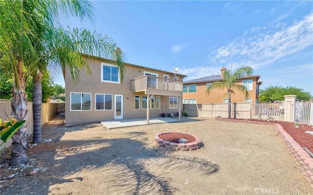 back of property featuring an outdoor fire pit and a balcony