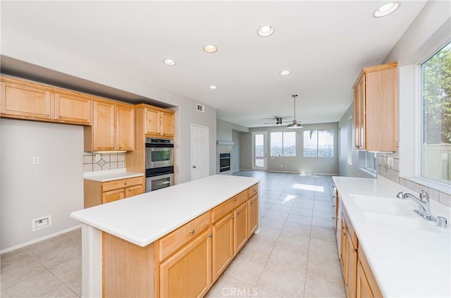 kitchen with ceiling fan, decorative backsplash, sink, plenty of natural light, and stainless steel double oven