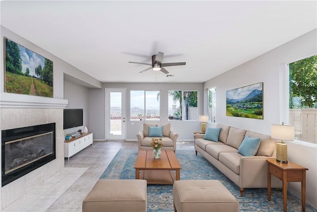 tiled living room with ceiling fan and a fireplace