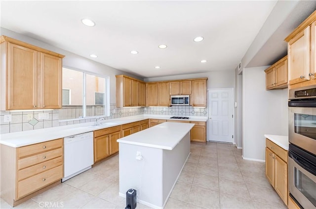 kitchen featuring a kitchen island, decorative backsplash, sink, appliances with stainless steel finishes, and light tile patterned floors