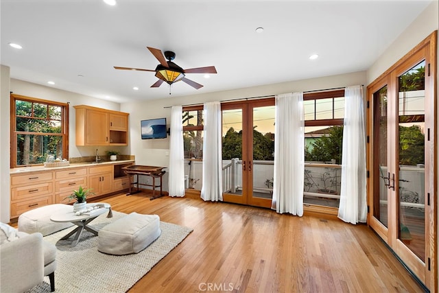 living room featuring french doors, sink, light wood-type flooring, and ceiling fan